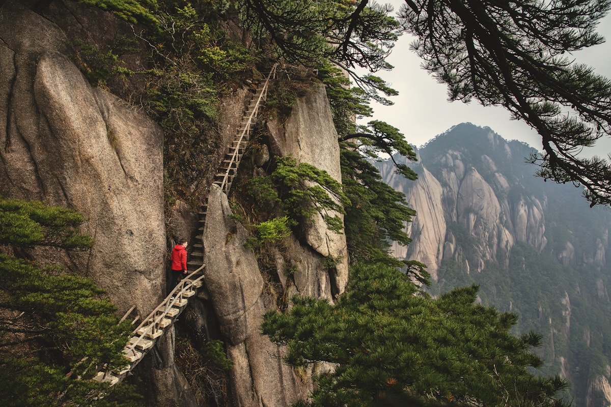 Huangshan's West Sea Grand Canyon — steep stone staircases carved into near-vertical granite cliffs, mist swirling through the gorge below
