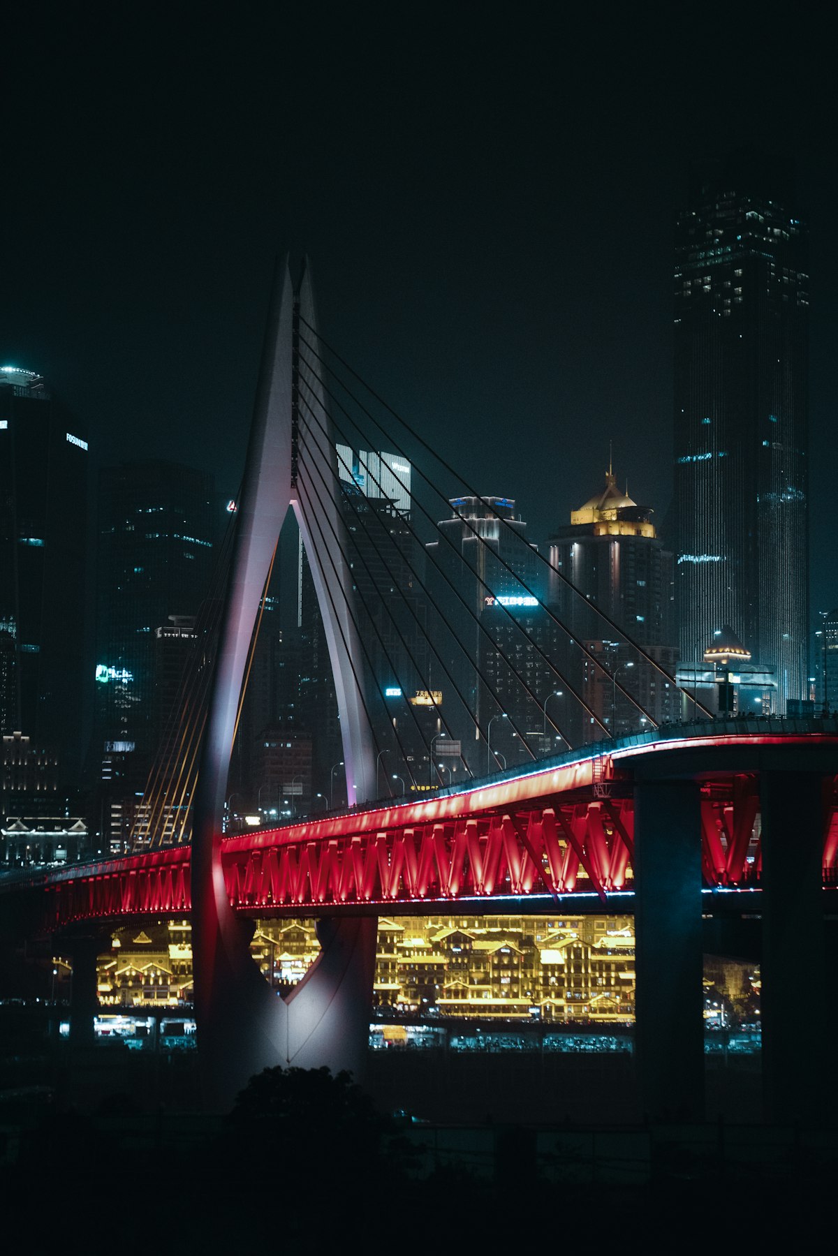Chongqing's layered skyline with elevated light rail and river at dusk