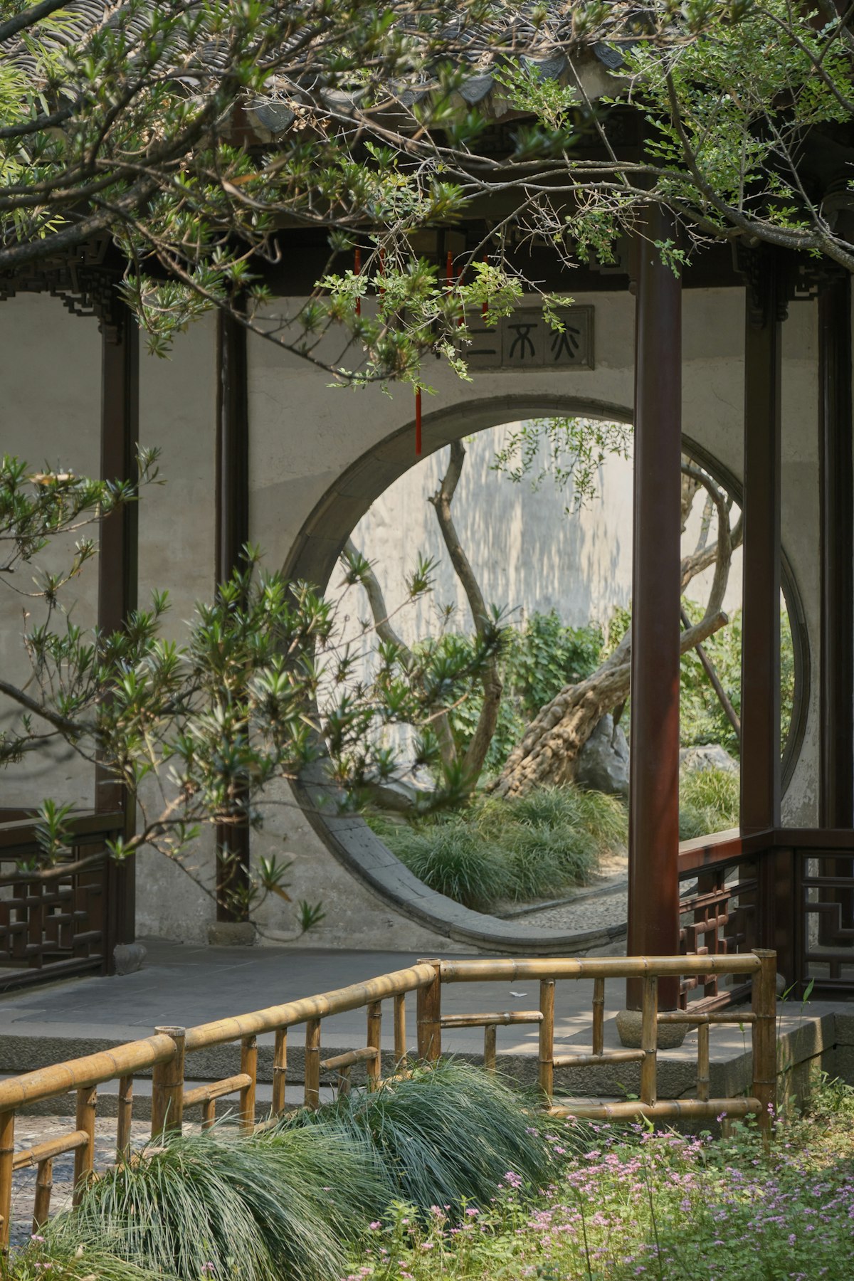 Traditional Chinese garden with circular moon gate reflecting in pond in Suzhou