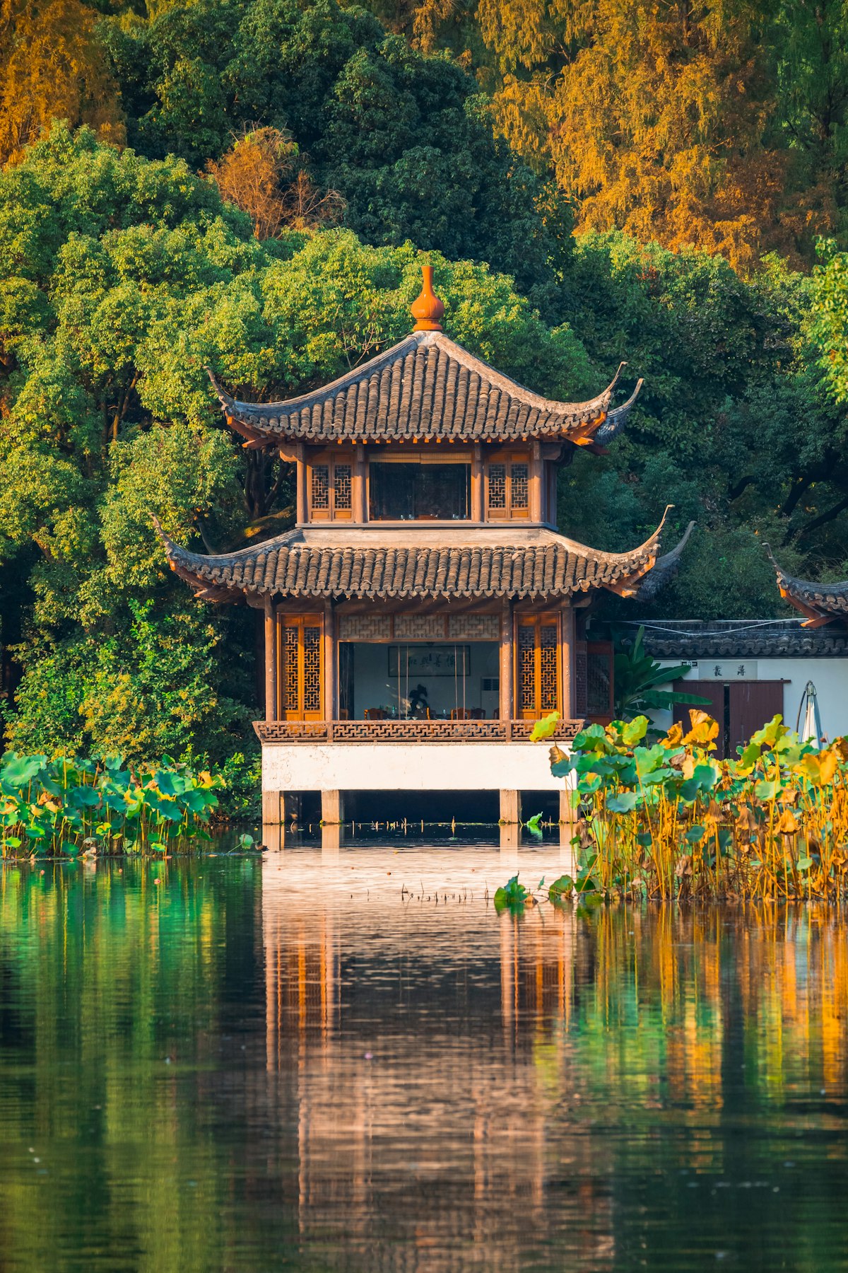 Traditional Chinese pavilion overlooking West Lake in Hangzhou with lush green hills